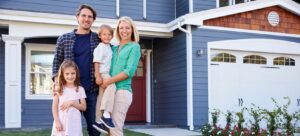 Family in front of a blue home with a white carriage style garage door