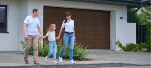 Family in front of a modern garage door - faux wood appearance